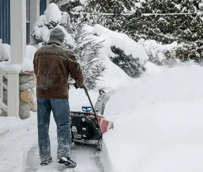 Residential snow removal technician using a snow blower to clear a home driveway and walkway in New Haven, CT